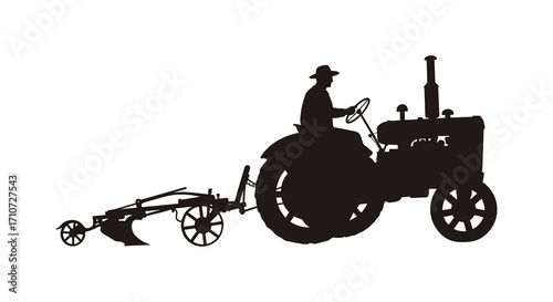 Silhouette of a farmer driving an antique tractor in a field