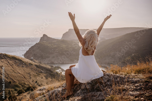 Wallpaper Mural Happy woman is sitting on a hillside, wearing a white dress. She is surrounded by a beautiful landscape, with a body of sea in the background. Concept of peace and happiness. Torontodigital.ca