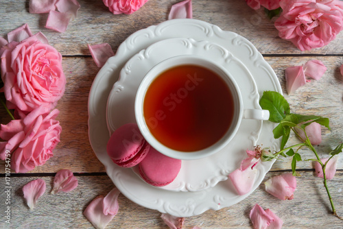 A cup of aromatic tea, a book and a rose on the table.