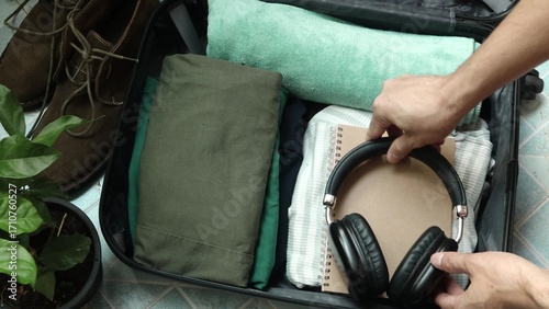 Close up of an unrecognized person getting ready for travel and packing clothes into an open black suitcase, vacation travel concept. Person preparing for a trip and folding clothes into a luggage