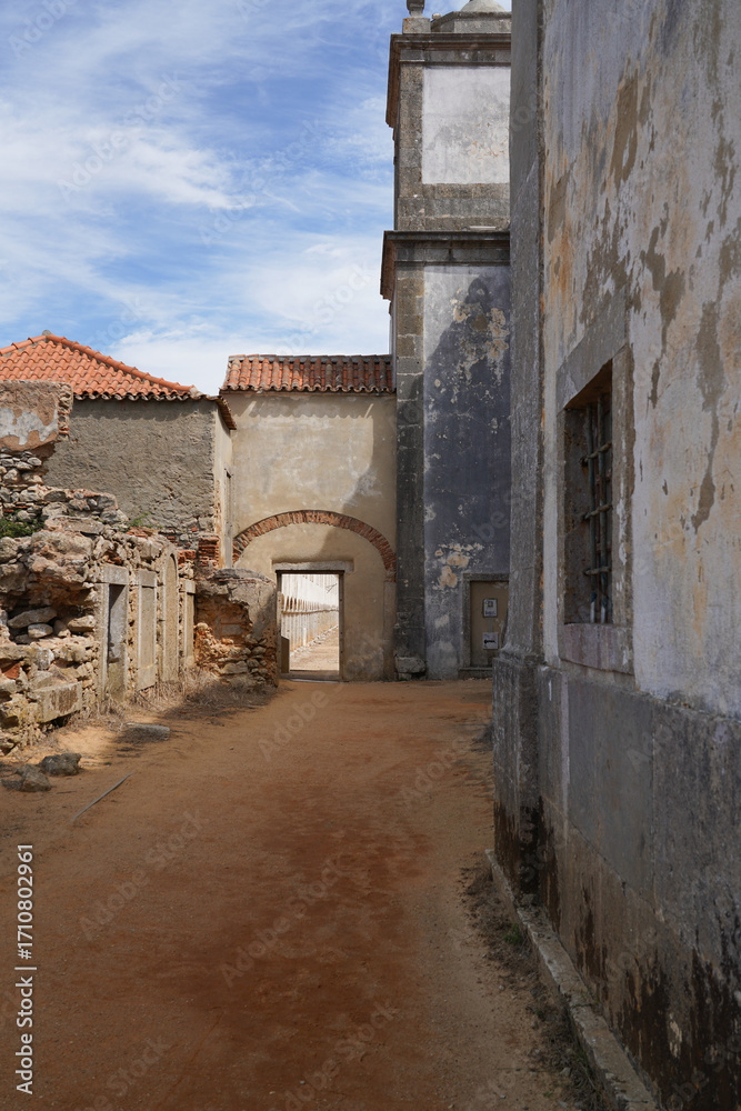 Fototapeta premium Old religious structure with archway on the coast of Portugal. Stone architecture, spires, pathway, historic atmosphere, religious symbolism, peaceful scene.