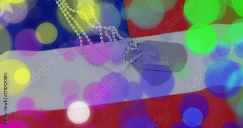 Obraz Displaying military dog tags on ball chain lying flat on American flag, with colorful bokeh overlay