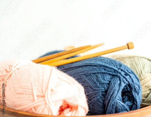 Colorful yarn balls and knitting needles in a bowl