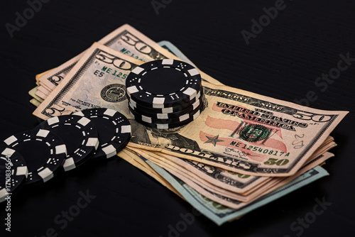 Stacks of poker chips with money on black background