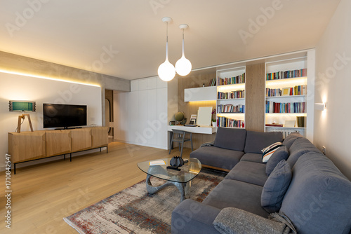 Interior of a modern living room with a large bookshelf, a sofa, and a wooden sideboard