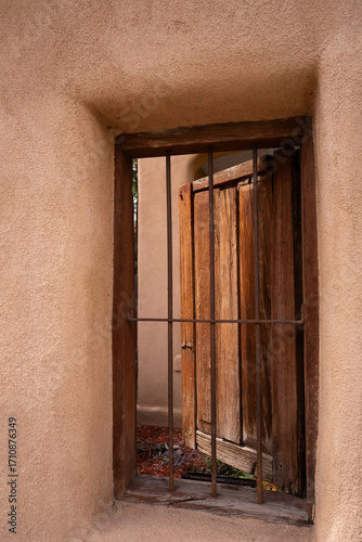 Fotografi large antique wooden door open behind an iron gate or door in an adobe home in Santa Fe, New Mexico U