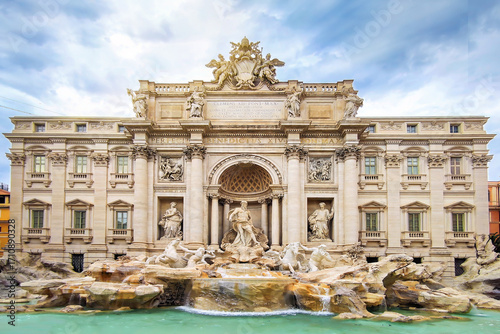 Trevi Fountain (Fontana di Trevi) in Rome, Italy, a famous iconic landmark featuring Baroque architecture, sculptures, and turquoise water under a dramatic cloudy sky on a summer day