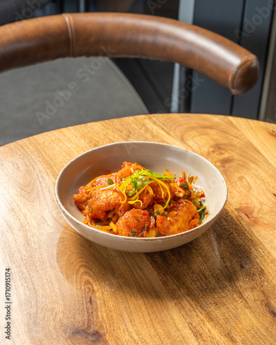 Authentic Chinese, stir fried fish plated in a bowl kept on a wooden table