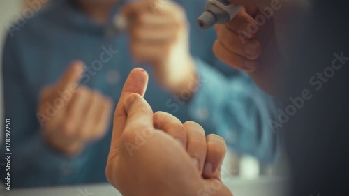 In the morning, in the soft light of the bathroom, a man checks his sugar level in front of the mirror. Close-up of his hands carefully pricking his finger with a lancet. Concept - body care