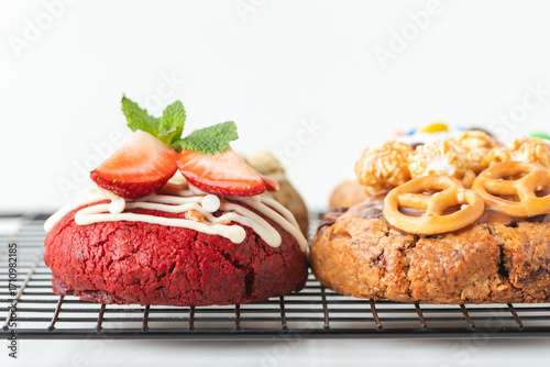Assortment of fresh chocolate American chip cookies with salted camel, caramel popcorn, matcha tea , marshmallow and colorful candies on white background. Different cookies on cooling rack