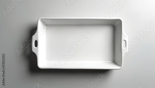 Clean white porcelain rectangular baking dish with handles sits on a grey surface. The empty kitchenware is viewed from above, perfect for recipes or food blogs.