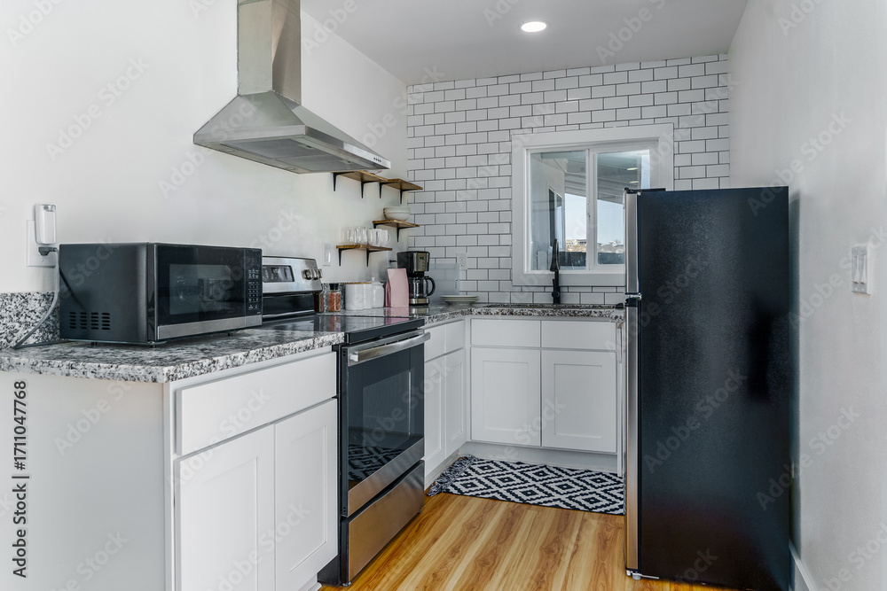 Fototapeta premium Bright white kitchen with stainless steel appliances and subway tile