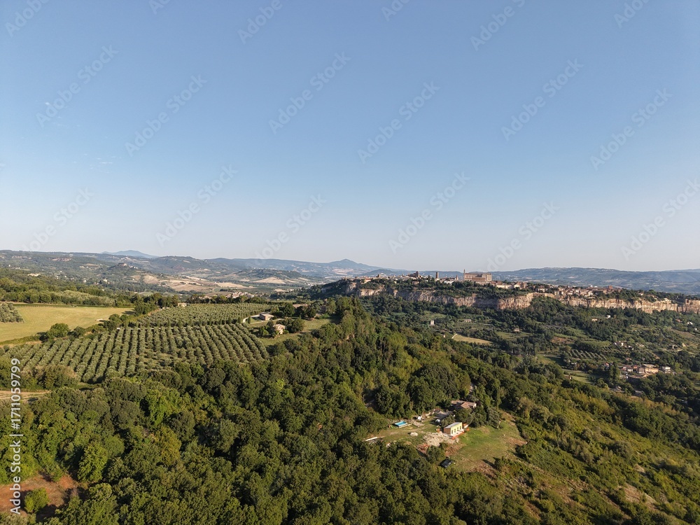 Obraz premium Aerial drone photo of Orvieto, a historic town in Umbria, central Italy, dramatically perched on a volcanic plateau. The view captures the hilltop town surrounded by olive groves, lush countryside.