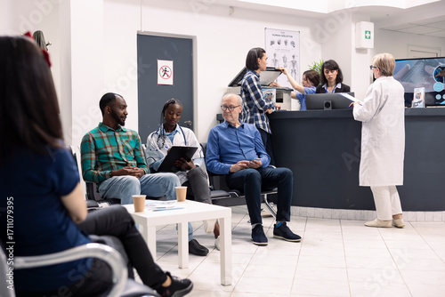 Schilderij op canvas Female doctor listening attentively to concerns from two diverse male patients during health consultation in hospital reception area