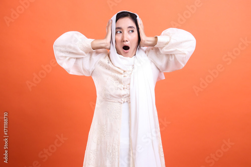 фотографія Startled veiled woman with a wide-eyed expression, holding her h