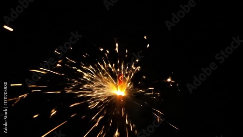 Close up of a festive sparkler burning with golden sparks on a black background.