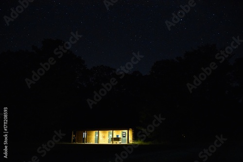 nighttime shot of a cabin lit up by a light from a window