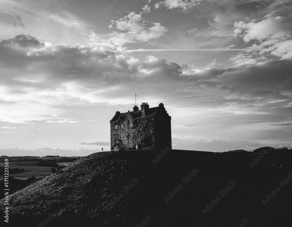 Obraz premium Castle perched on hilltop with dramatic clouds