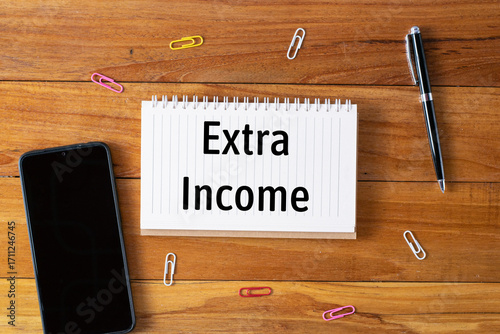 Extra Income written in a notebook on wooden desk