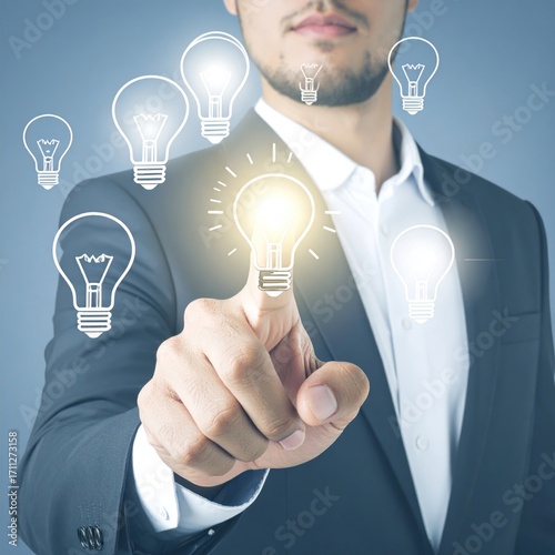 Man in suit points at a glowing lightbulb amidst other unlit bulbs, symbolizing ideas, inspiration, and innovation against a blue background