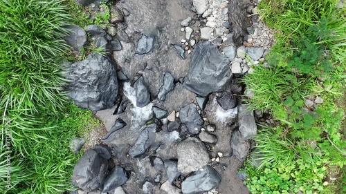 Gentle Creek Flowing Between Green Grass And Dark Rocks Scenery
