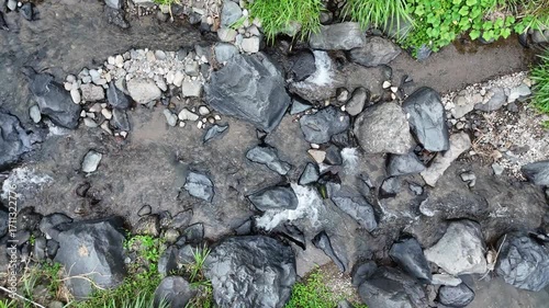 Small Stream Flows Through A Rocky Valley With Green Vegetation