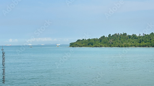 Serene Coastal Landscape with Calm Blue Water and Green Island Under Clear Sky