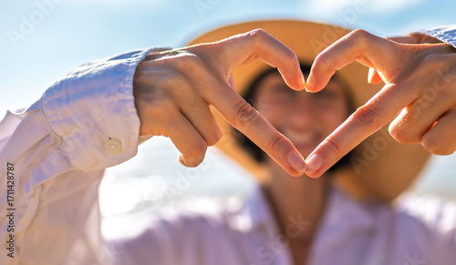 A girl made a beautiful heart with her finger. A cheerful girl makes a heart shape with her hands against a backdrop of sea and sky.