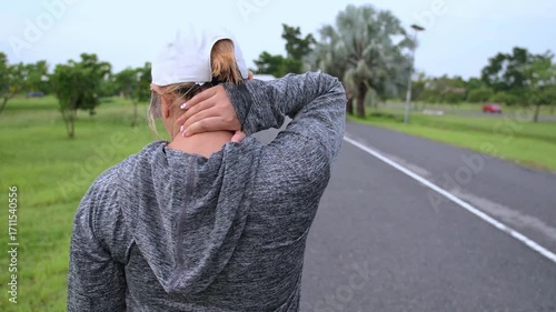 Video of Asian woman walking outdoors, massaging stiff neck—sign of morning muscle tension or strain. Ideal for ads on neck pain, wellness, and physical therapy care.