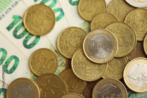 Big amount of euro cent coins lies on hundred euro bills banknotes