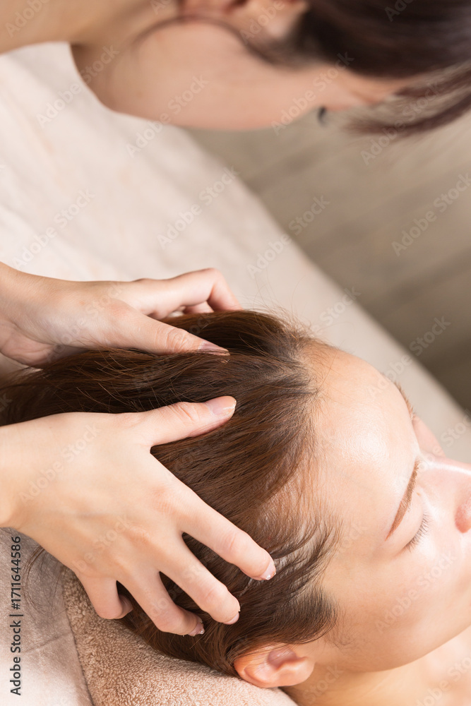 Fototapeta premium 若いアジア人のエステティシャンはヘッドマッサージしている。