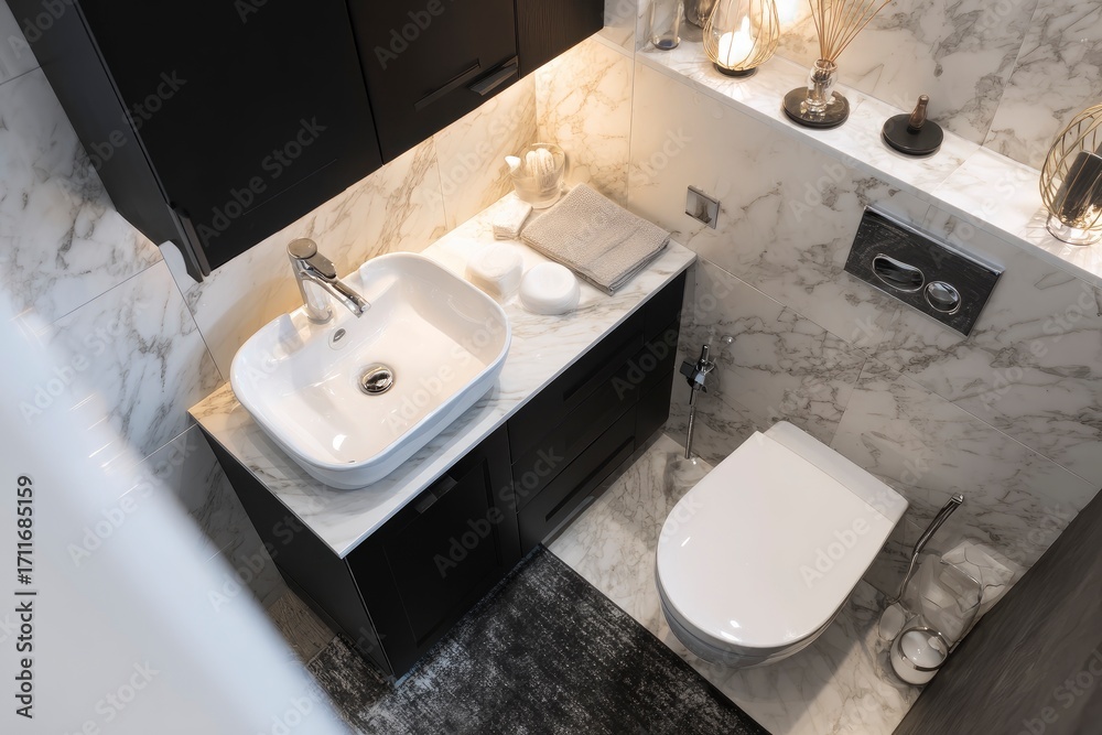 Fototapeta premium Highangle view of a modern bathroom featuring a sleek sink toilet marble tiles and black cabinets