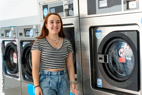 Young woman smiling and washing clothes in laundromat