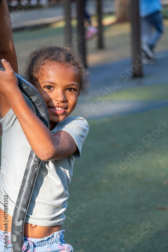 African American girl joyfully playing on playground equipment, showcasing her playful spirit and innocence during a sunny summer day with vibrant outdoor surroundings and sense of childhood happiness