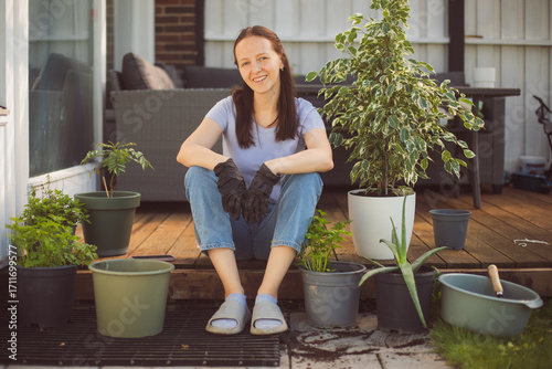 Happy woman gardening at home, repotting houseplant ion outdoor terrace at home