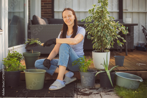 Happy woman gardening at home, repotting houseplant ion outdoor terrace at home