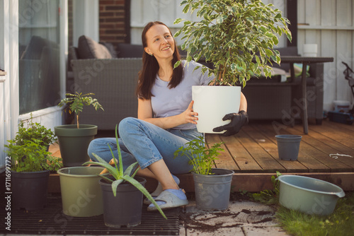 Happy woman gardening at home, repotting houseplant ion outdoor terrace at home