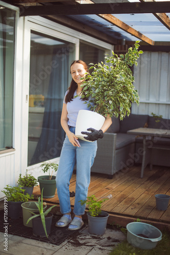 Happy woman gardening at home, repotting houseplant ion outdoor terrace at home