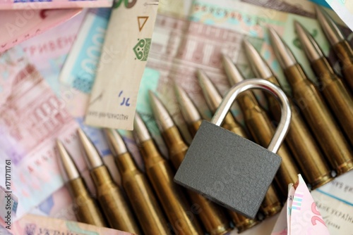 Big amount of different Ukrainian hryvnia money bills and bullets with padlock