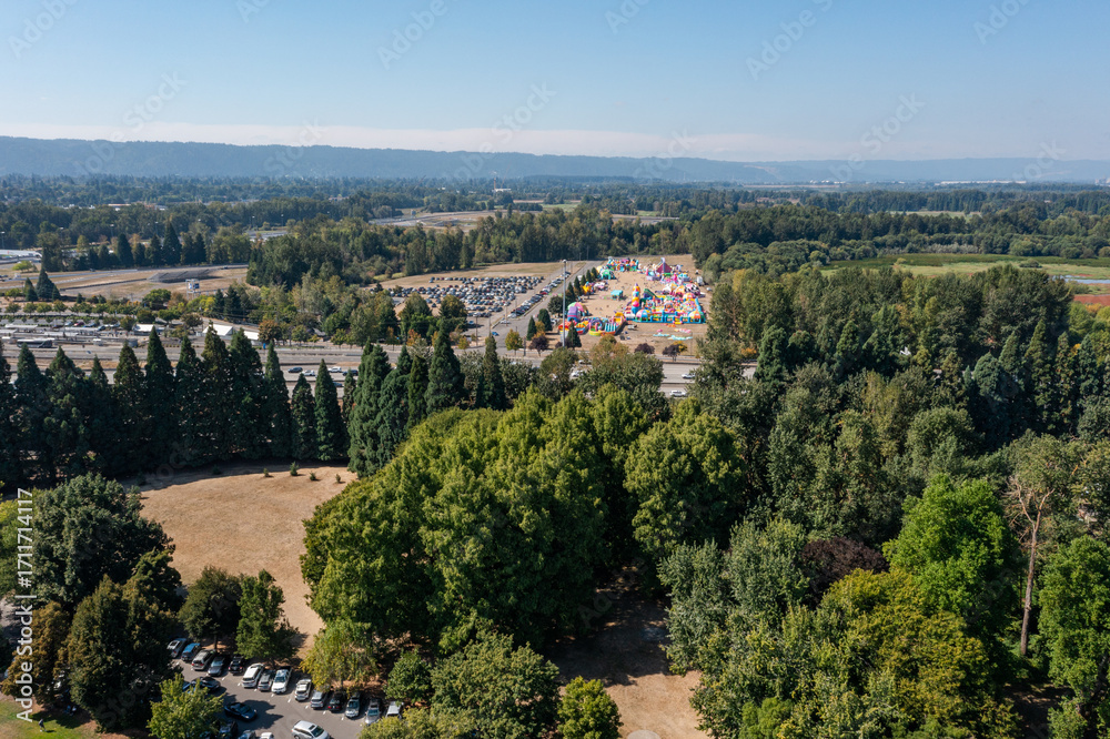 Fototapeta premium Aerial drone photo of a colorful outdoor play park and event area for kids, near Portland International Raceway and Interstate 5 in North Portland, with a huge busy parking lot, under blue sky