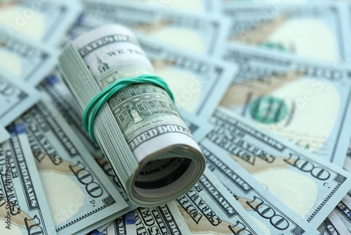 Roll of hundred dollar bills USD banknotes lies on big amount of united states money
