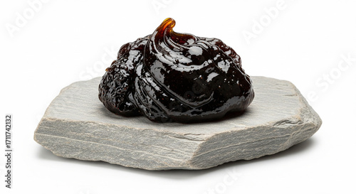 45 degree view of Shilajit resin on natural stone slab isolated on white