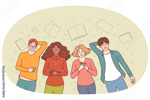 Group of happy students lie on grass in park and smile, enjoying sunny summer day. Positive guys and girls are relaxing in park, throwing textbooks aside and forgetting about studies.