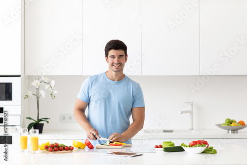 Attractive young fit man is preparing healthy vegetable food while