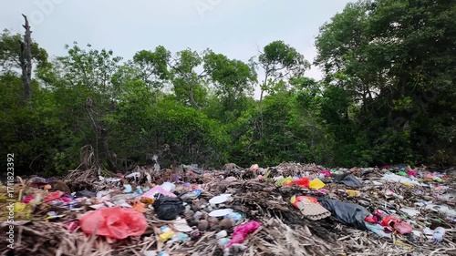 A road with trash on it. The trash is mostly plastic bottles. There are also some trees in the background