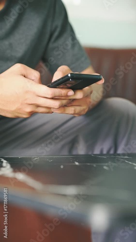 Close up man using smartphone in home for online shopping, browsing internet and communications. Generation Z lifestyle people hand holding phone text Chatbot digital technology or remote working 
