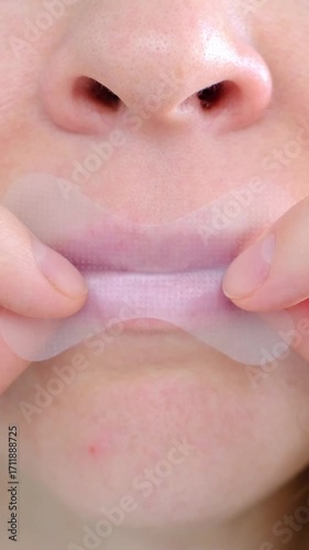 A girl puts a snoring patch on her mouth, close-up to sleep with her mouth closed and breathe through her nose. Healthy sound sleep with proper breathing. The toned oval of the face. Wellness