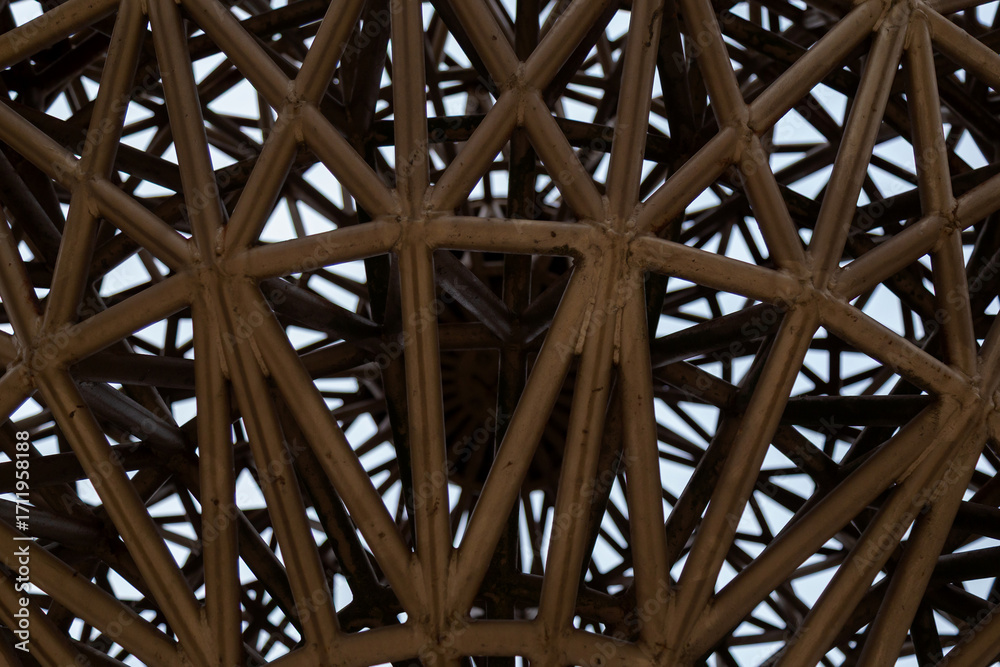 Obraz premium Detailed close-up of an intricate geometric structure made of metal beams. Perfect for architecture, interior design, metal constructions, engineering, decorative elements, and visual projects 