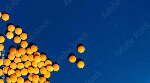 Foto Many orange tablets on blue background, copy space