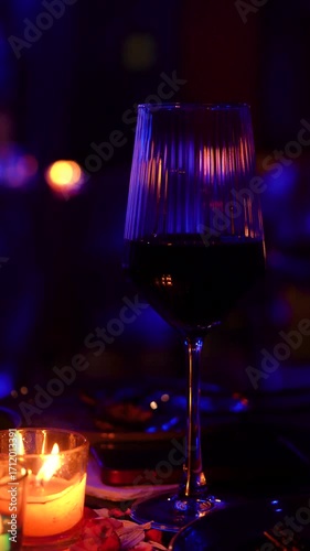Elegant wine glass on a table illuminated by candle flames, creating a warm and romantic club ambience